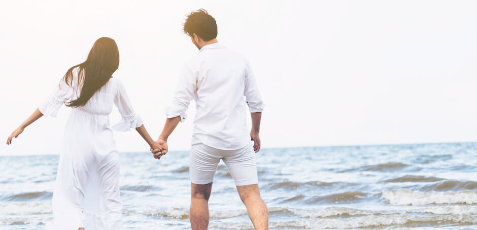 海辺で手を繋いではしゃぐ男女