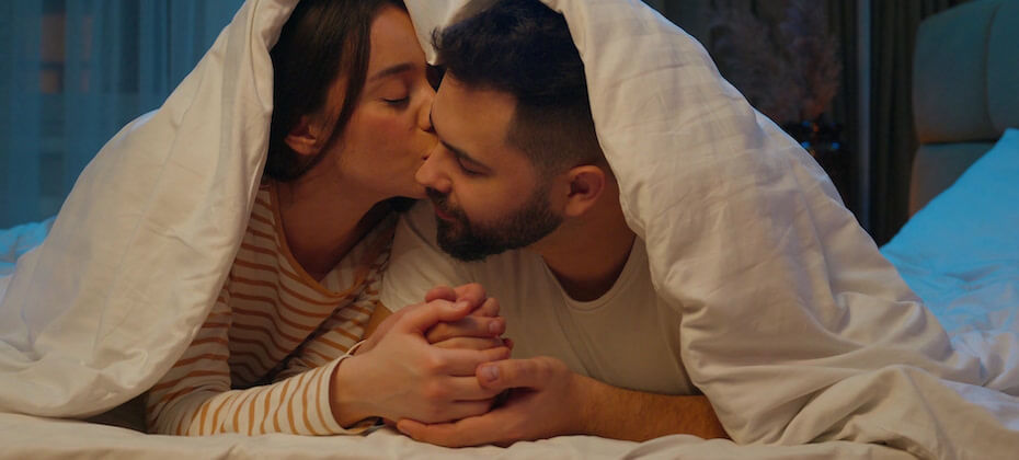布団を頭に被ってキスをする男女