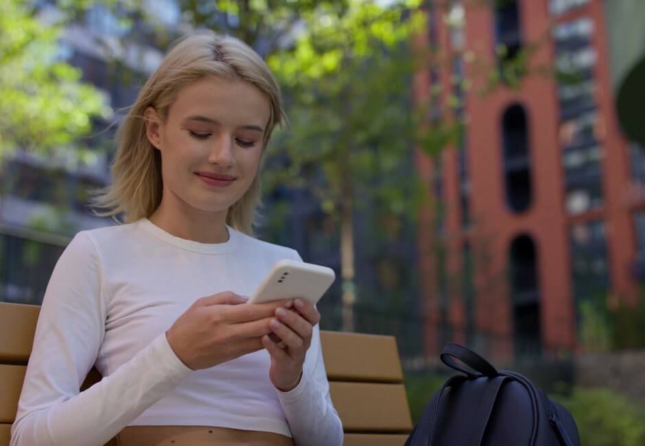 嬉しそうにスマホ画面を見つめる女性