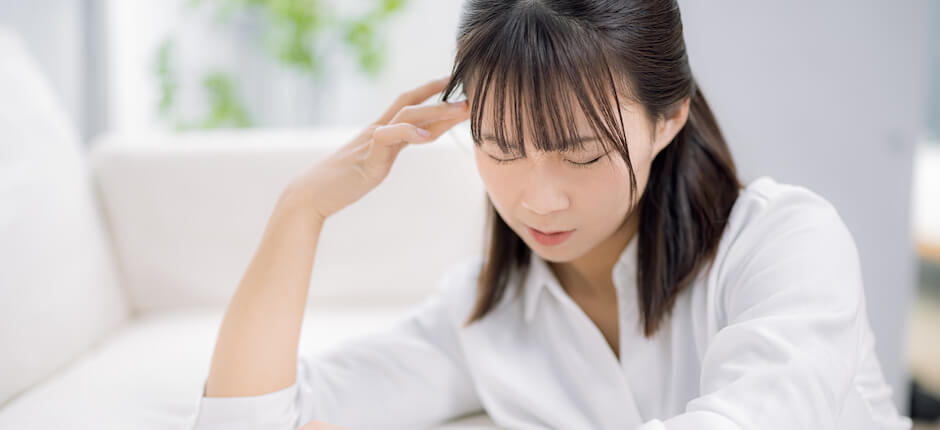 ソファにもたれかかって頭を悩ませている女性