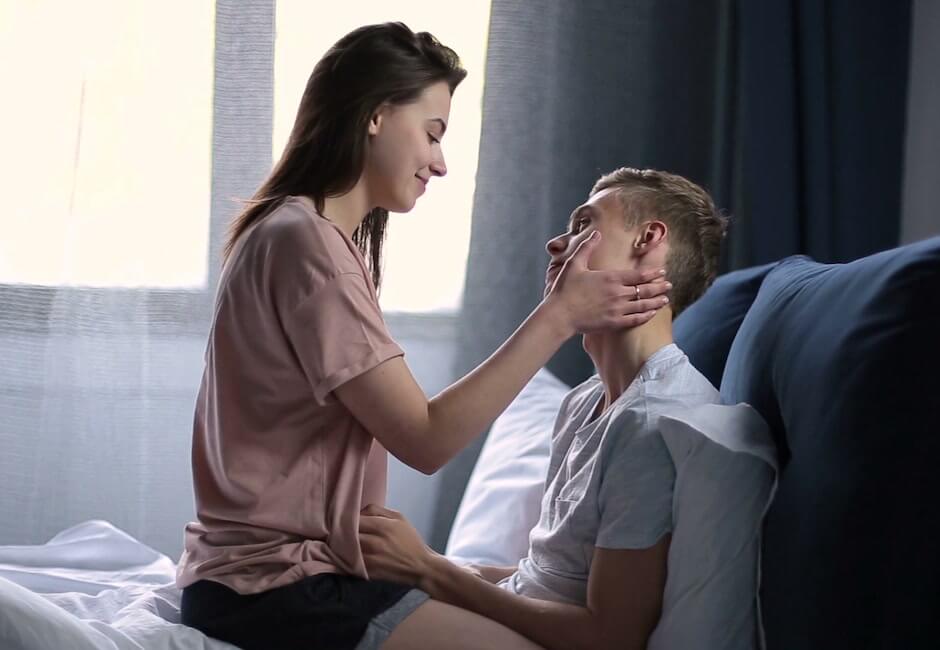 馬乗りになって男性の頬を両手で挟む女性