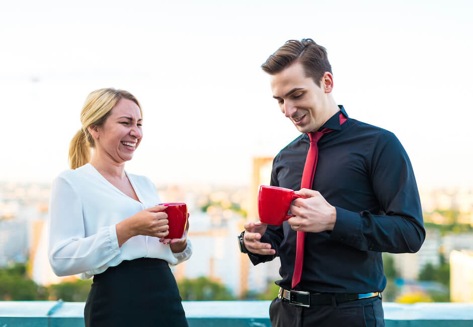 屋外でコーヒーカップを片手に談笑する男女