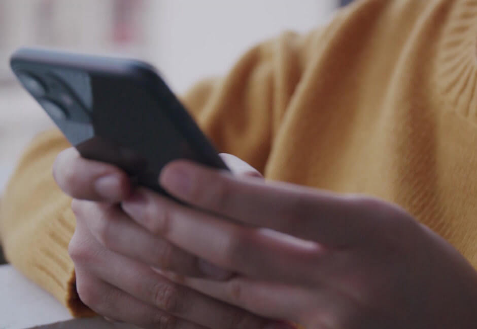 スマホ画面を見て返信がないか確認している女性