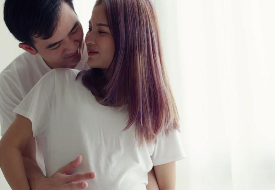 後ろから女性のお腹に触れる男性