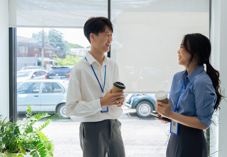 職場の窓付近で立って談笑している男女