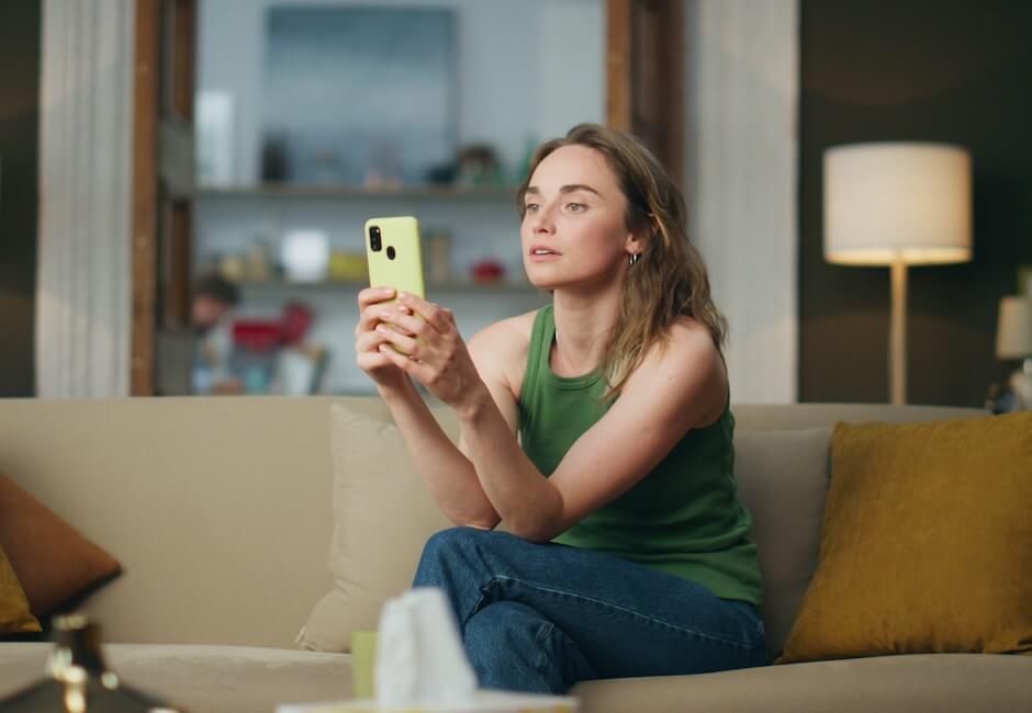 スマホ画面を見つめて考え込む女性