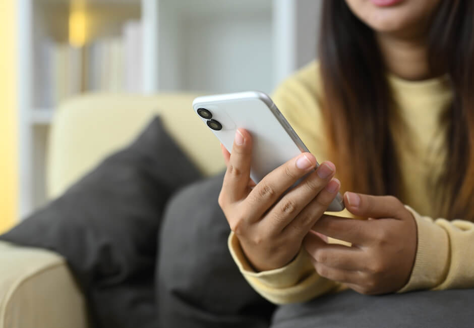 ソファに座ってスマホ画面を見つめる女性
