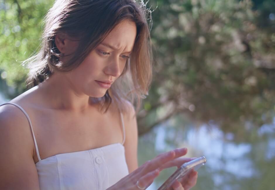 屋外でスマホ画面を見て立ち止まる女性